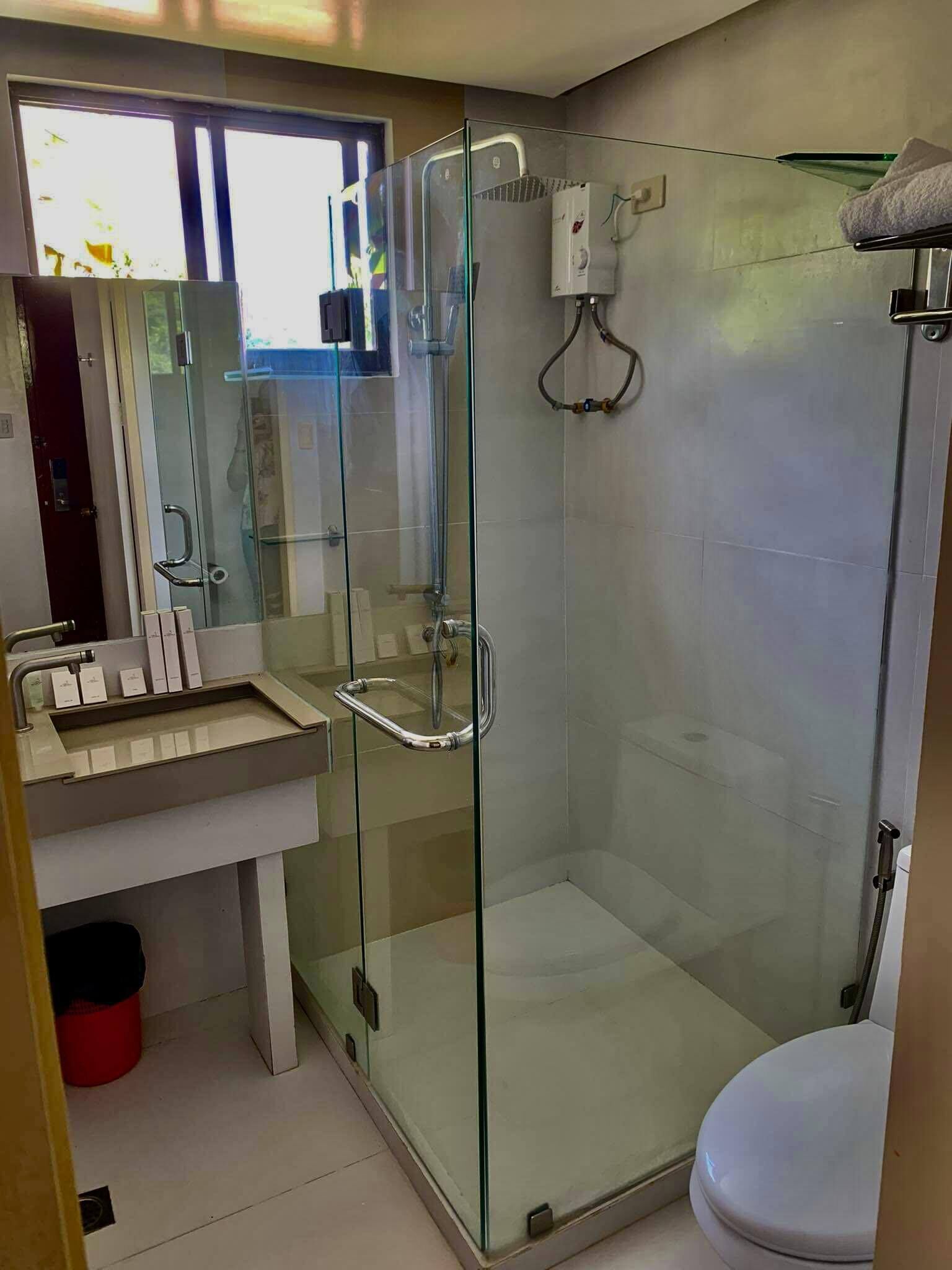 A modern bathroom with a glass-enclosed shower, a white sink, and a toilet.