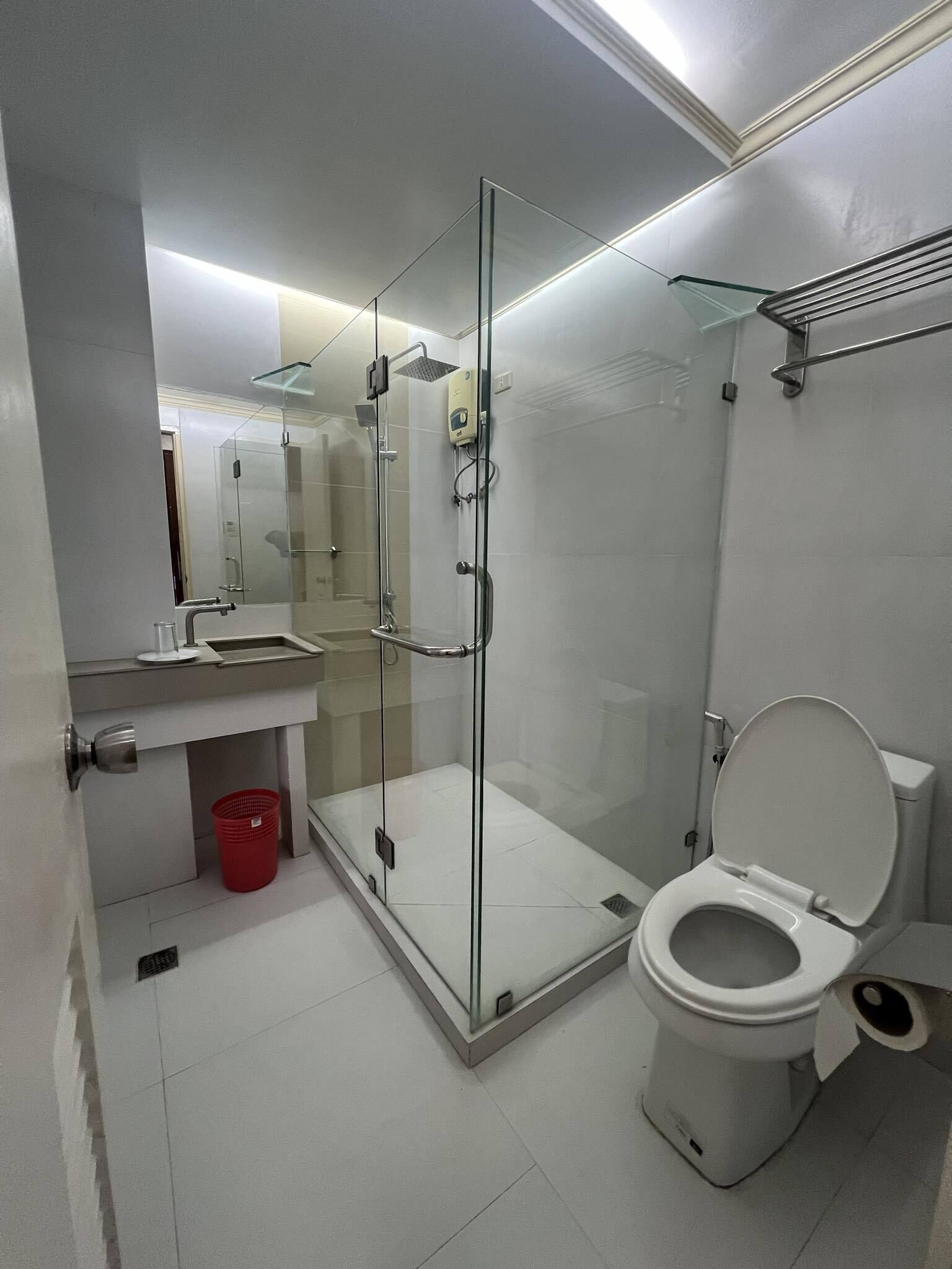A modern bathroom with a glass-enclosed shower, a toilet, and a sink.