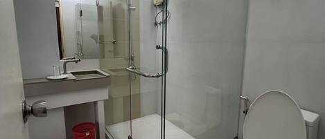 A modern bathroom with a glass-enclosed shower, a toilet, and a sink.