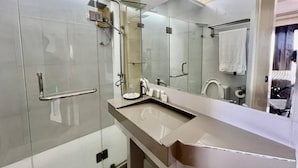 A modern bathroom with a glass shower enclosure, a vanity with a sink, and a large mirror.