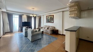 A spacious living room with a sofa set, a television, and a dining area with a cabinet.