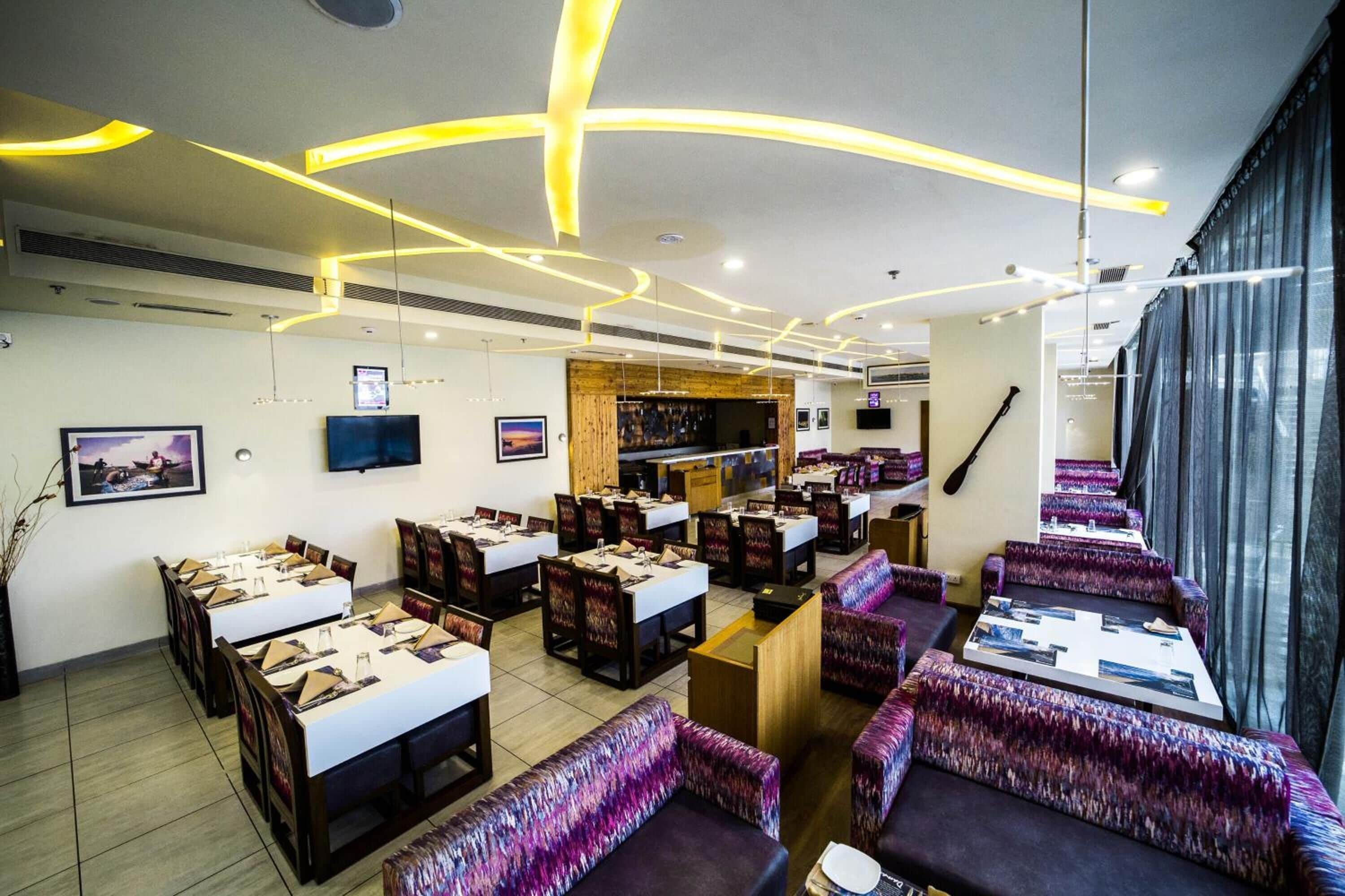Un ristorante con diversi tavoli e banconi, un'area bar e un'ampia finestra con tende.