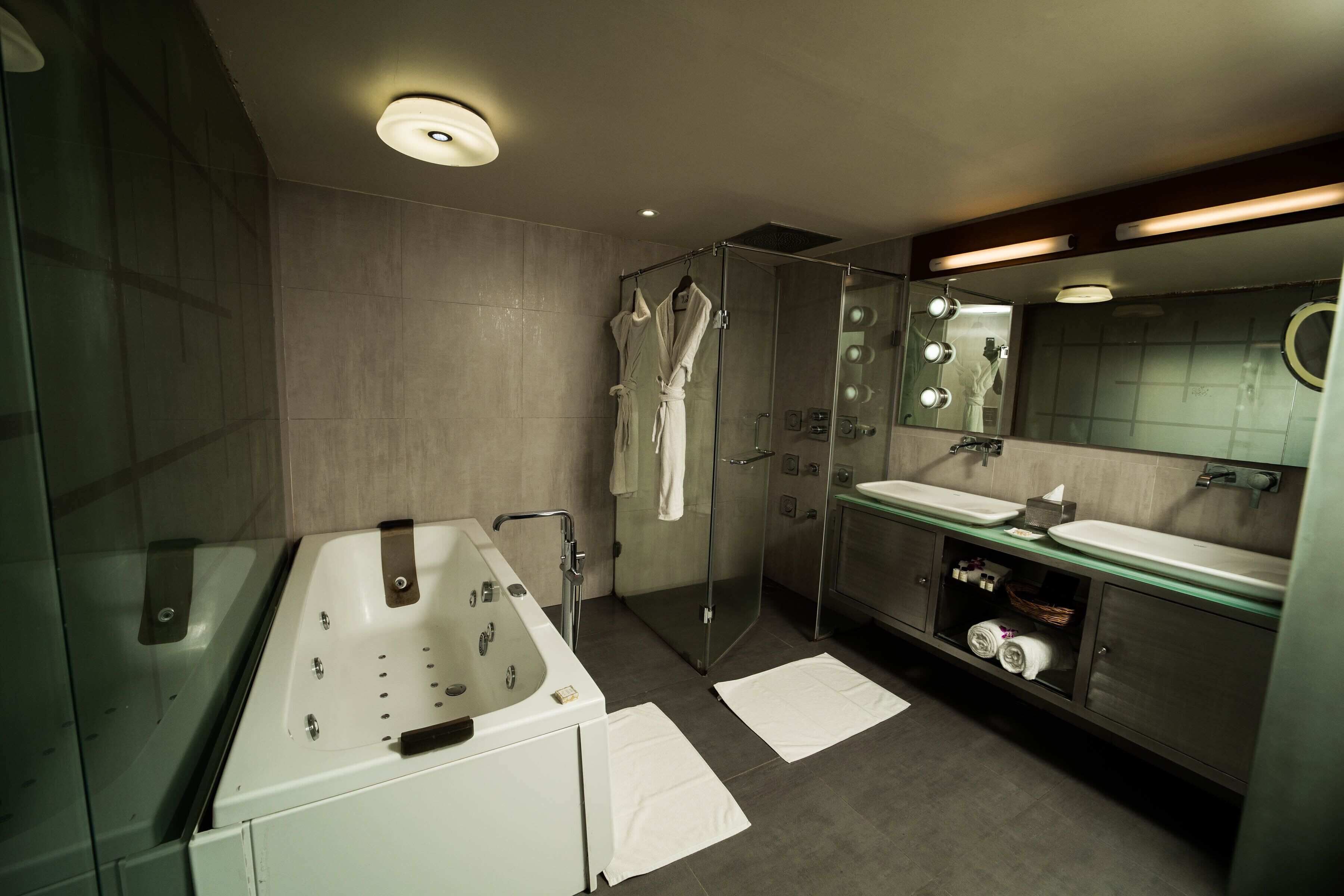 A modern bathroom with a glass-enclosed shower, a large bathtub, and a vanity with a mirror.