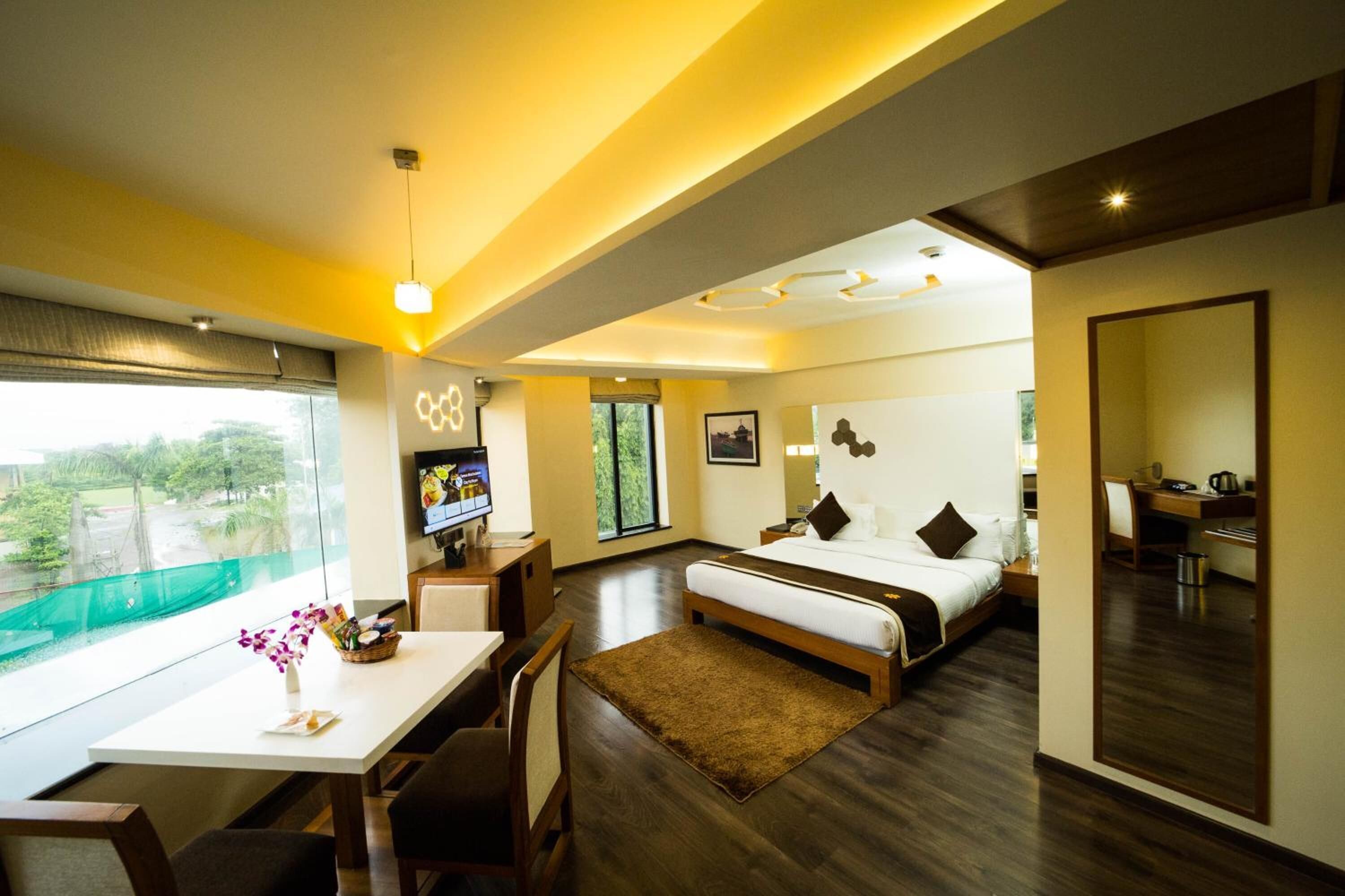 A modern hotel room with a large bed, a desk, and a TV.