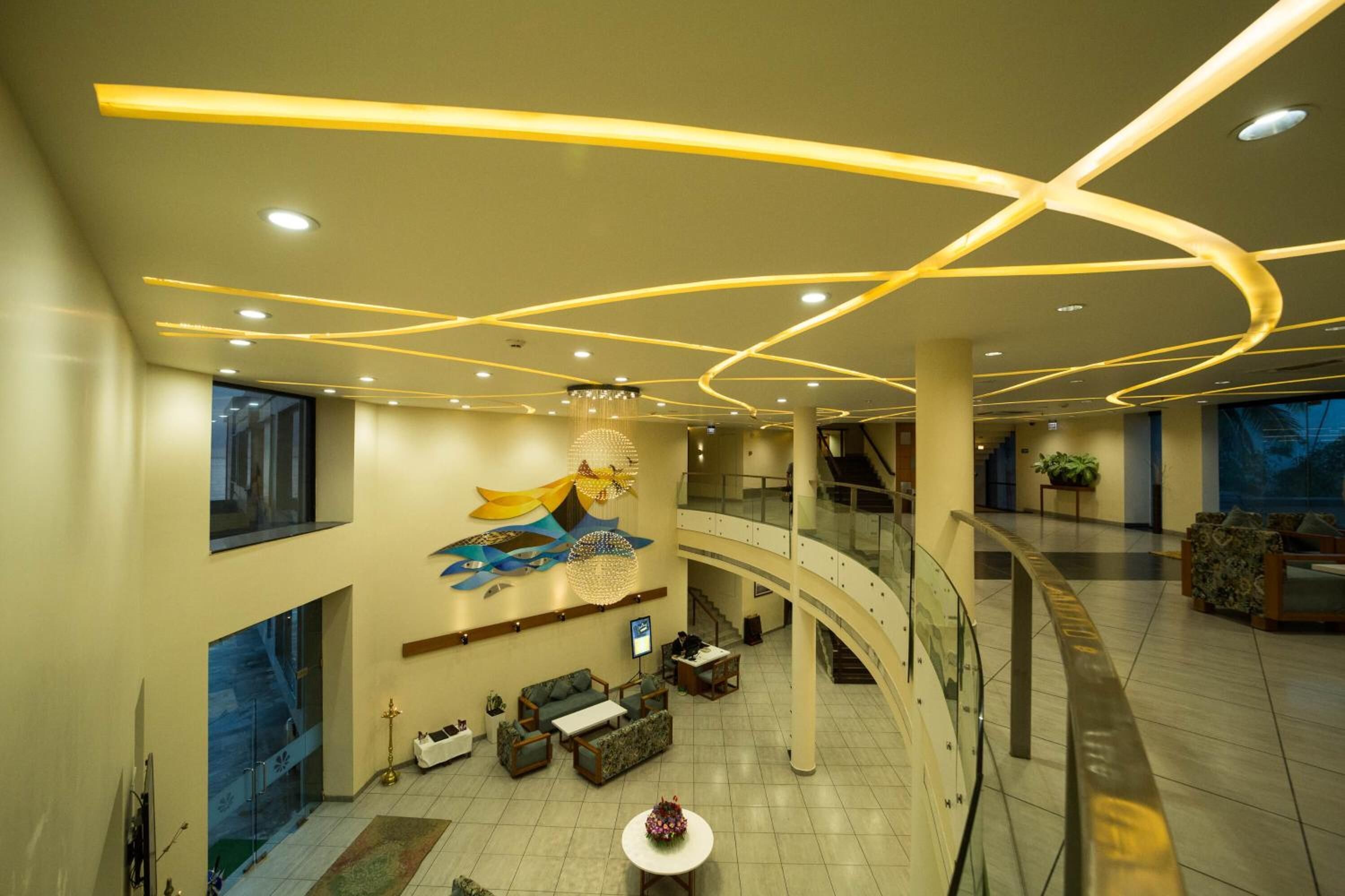 A spacious lobby with a curved staircase, a reception area, and a large wall mural.