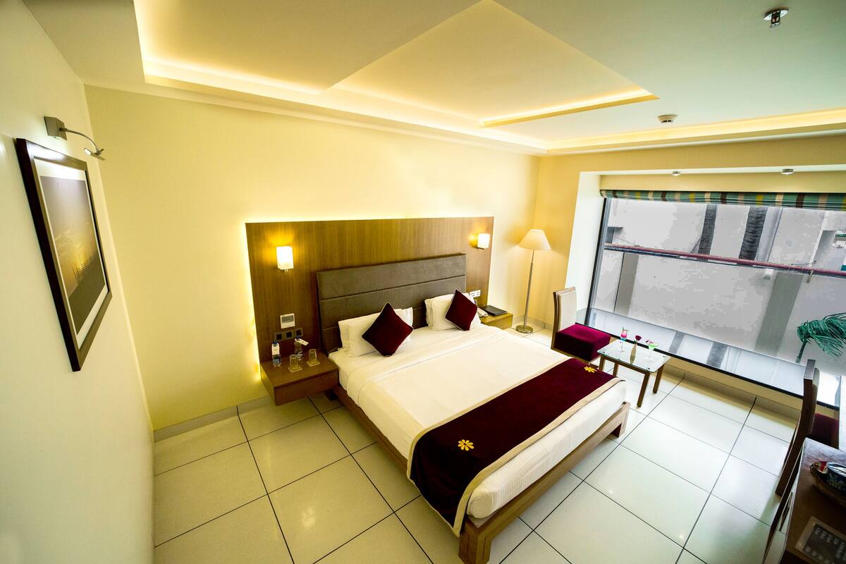 Hotelkamer met een groot bed, nachtkastjes, een raam met uitzicht en een plafondlamp.