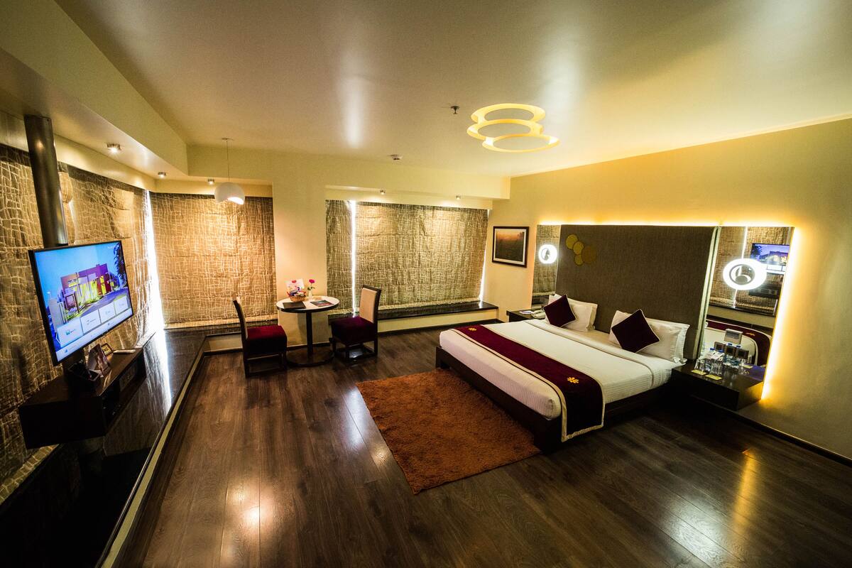 Een moderne hotelkamer met een groot bed, een televisie, een tafeltje en een stoel.