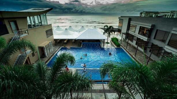 Una piscina con vistas al océano, rodeada de palmeras y arquitectura moderna.