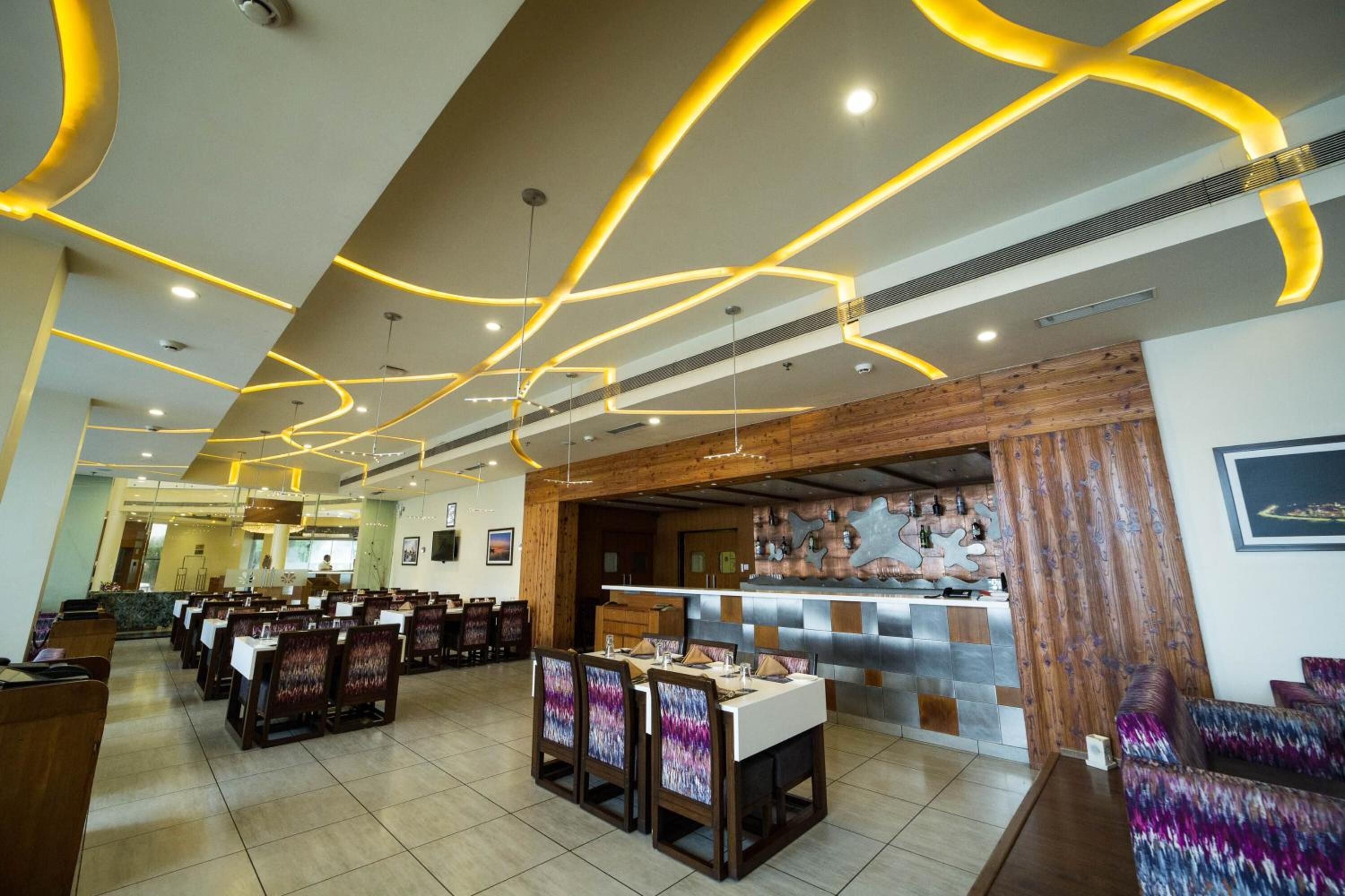 A restaurant with a modern interior, featuring a long counter and multiple dining tables with chairs.