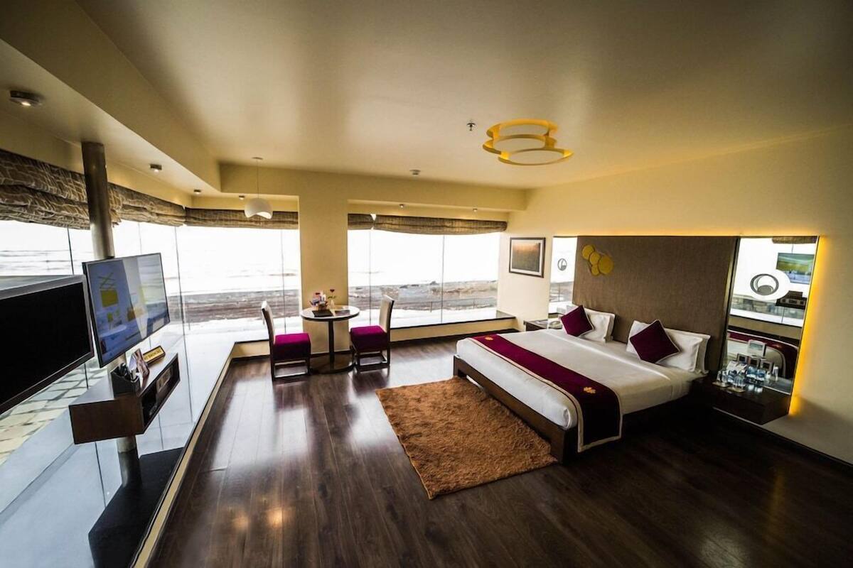 Een moderne hotelkamer met een groot bed, een televisie, een bureau en uitzicht op de oceaan.