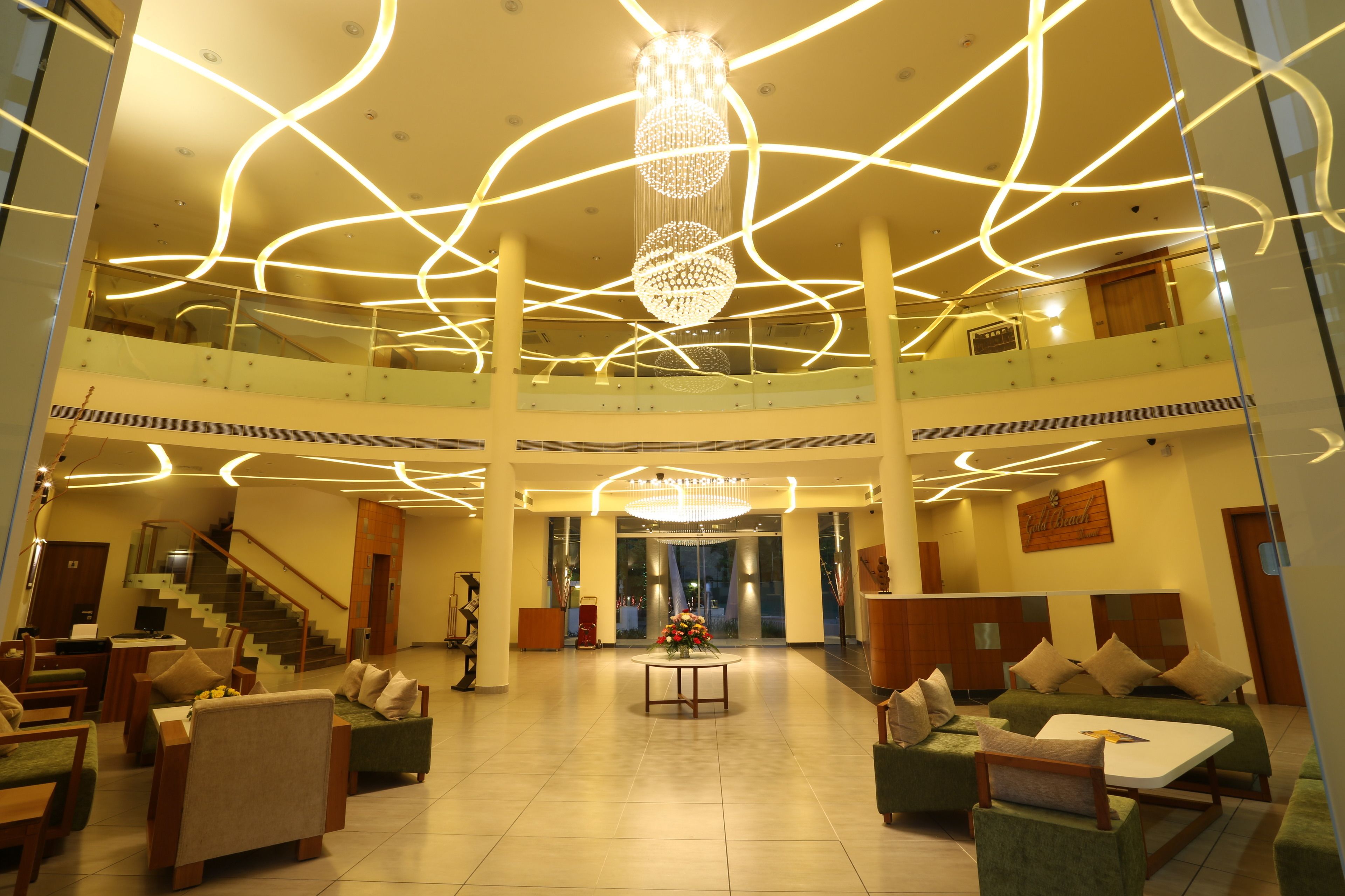 A spacious lobby with a chandelier, seating areas, and a staircase.