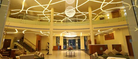 A spacious lobby with a chandelier, seating areas, and a staircase.