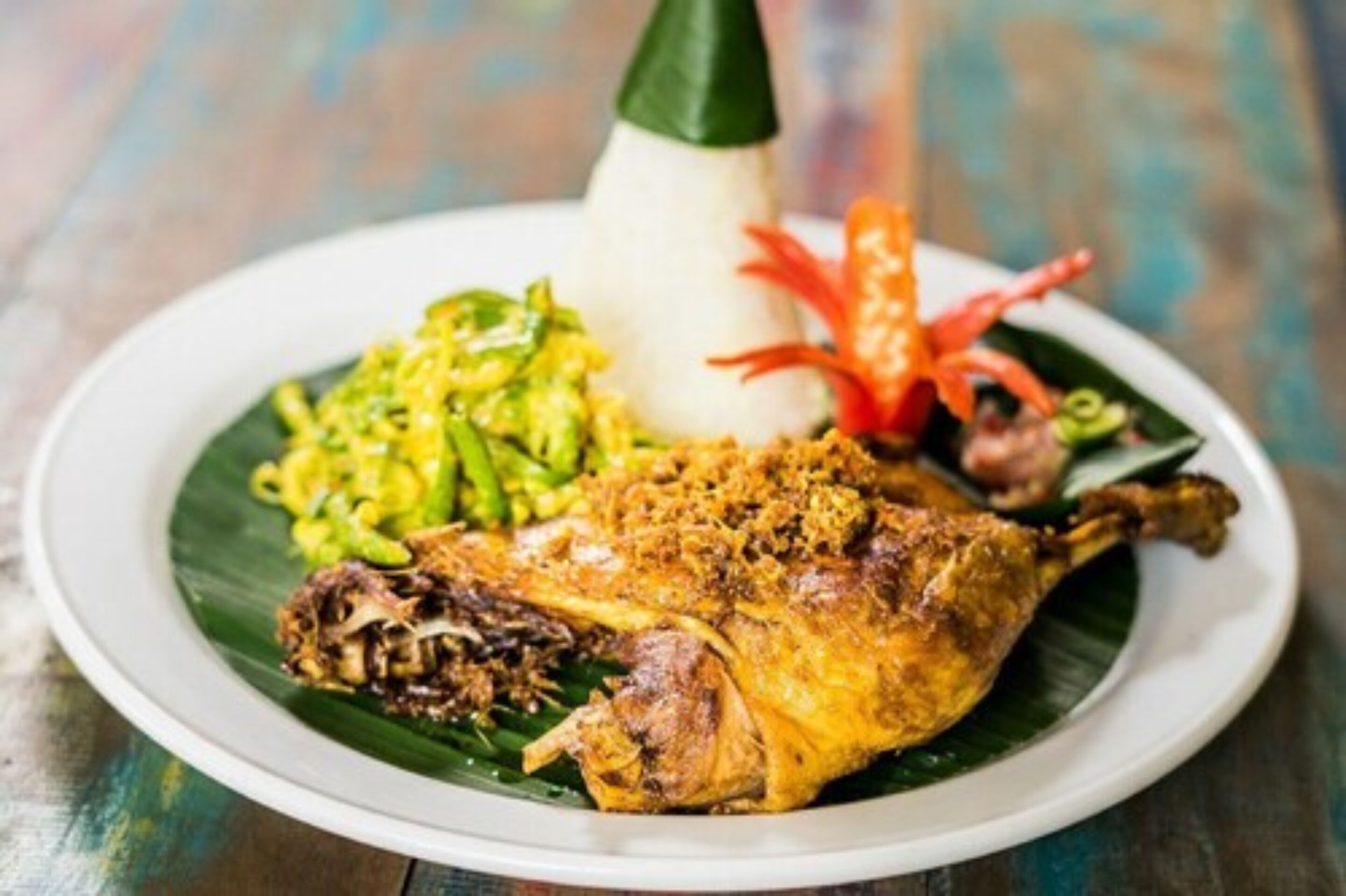 A plate of food with a roasted chicken leg, a mound of rice, and a side of green vegetables.