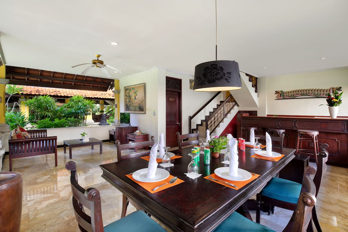 A dining area with a long wooden table set for a meal, surrounded by chairs.