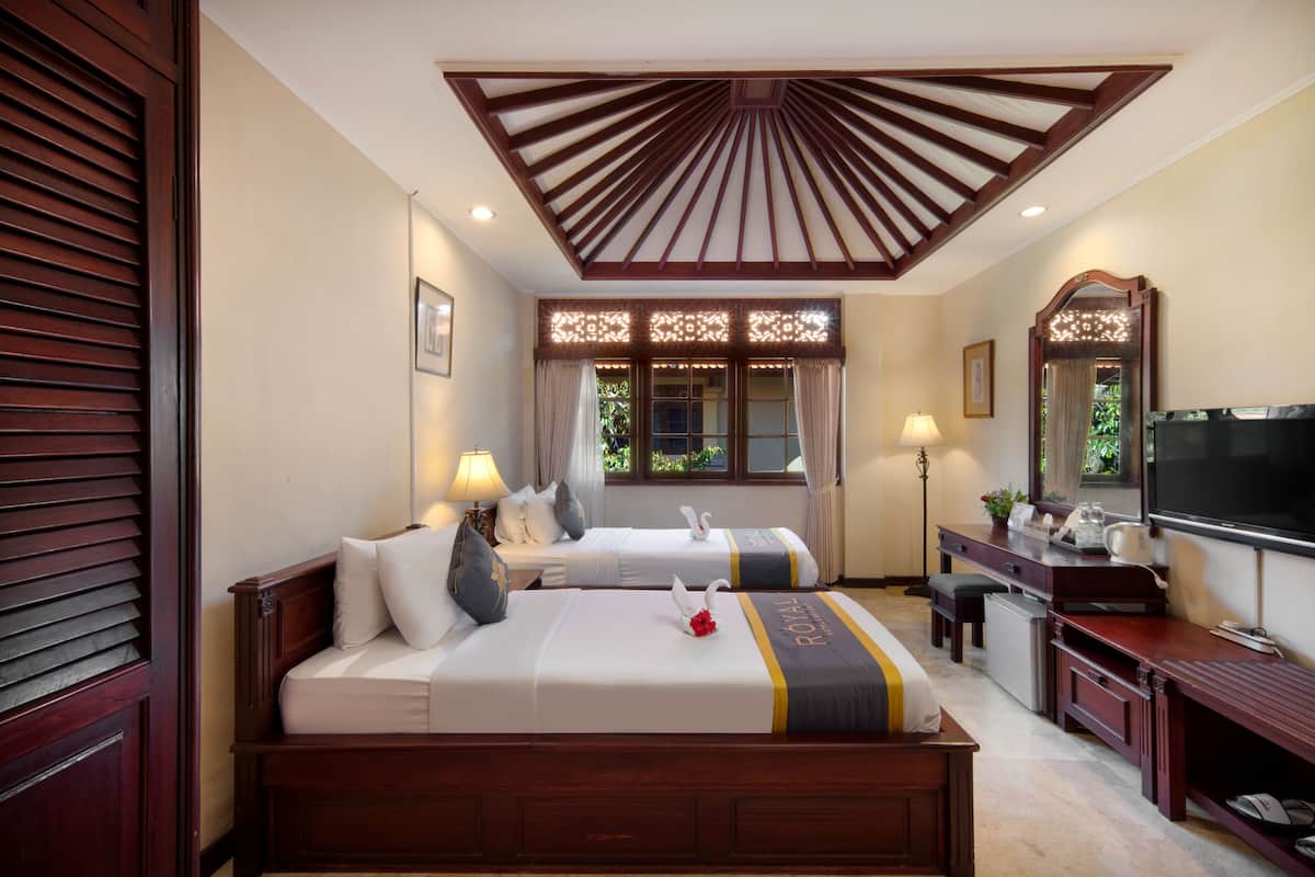 A hotel room with two beds, a desk, a TV, and a large mirror.