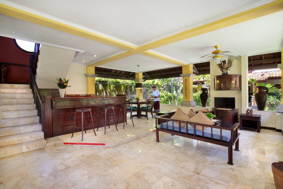 A spacious lobby with a marble floor, a wooden reception desk, a sofa, and a staircase.