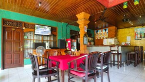 A restaurant with a wooden ceiling, red tablecloths, and wooden chairs. - Bali Senia Hotel (Denpasar)