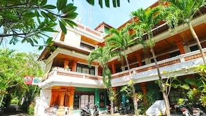 A traditional multi-story building with a central courtyard, surrounded by lush greenery and palm trees. - Bali Senia Hotel (Denpasar)