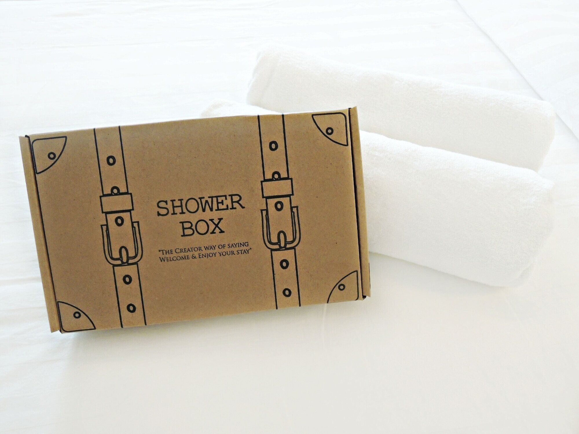 Eine braune Pappschachtel mit dem Aufdruck 'SHOWER BOX' und dem Spruch 'THE CREATOR WAY OF SAYING WELCOME & ENJOY YOUR STAY'.