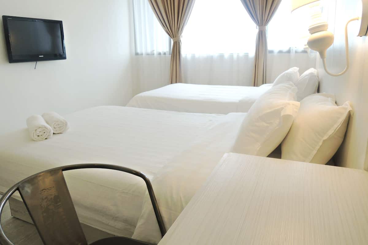 A hotel room with two beds, a flat-screen TV mounted on the wall, a desk, and a chair.