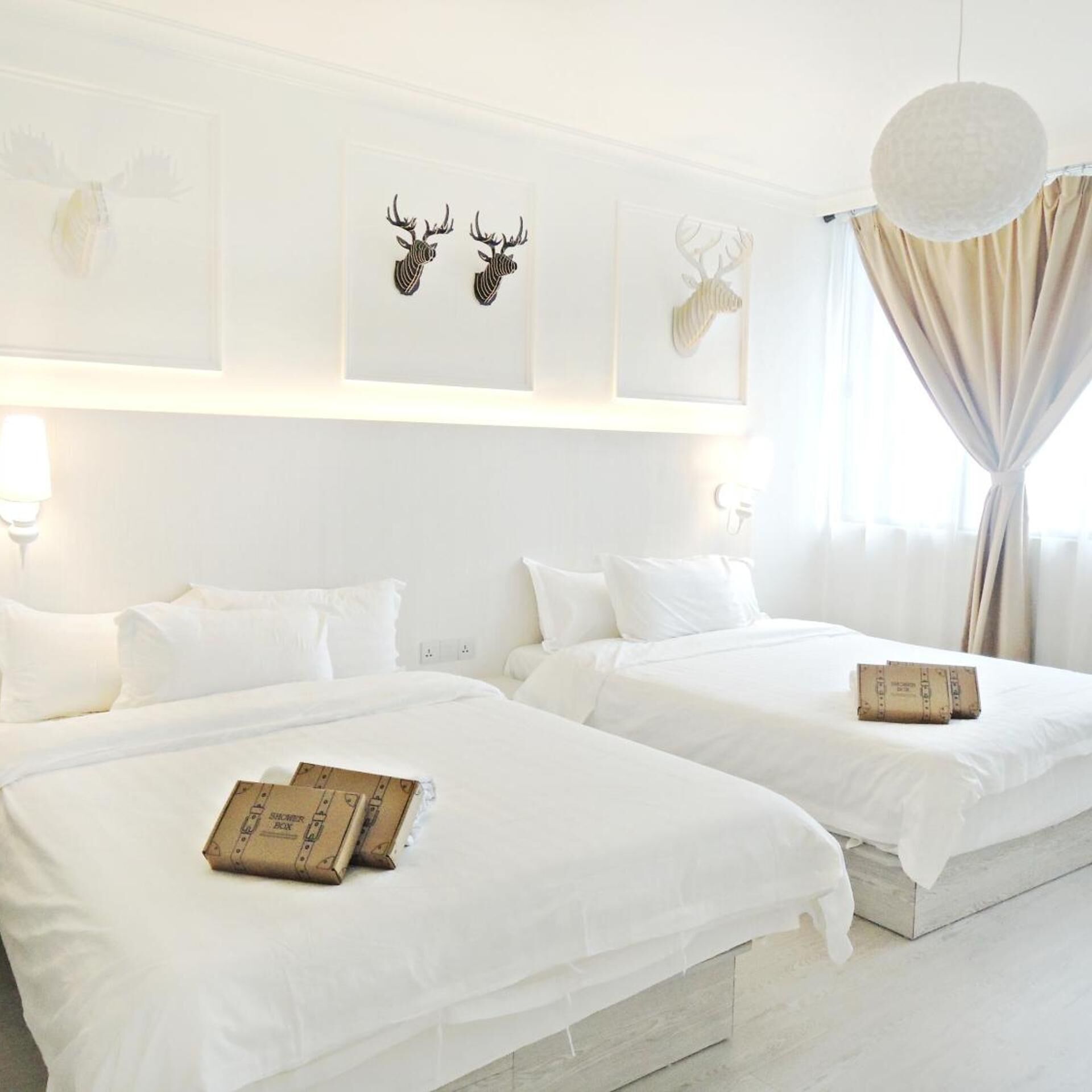 Habitación de hotel con dos camas, ropa de cama blanca y decoración en la pared.