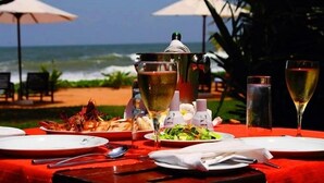 A table set for a meal with a view of the ocean, a pot on the table, and two wine glasses. - Temple Tree Resort & Spa (Induruwa)