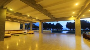 A spacious indoor area with a high ceiling, large windows, and a view of the ocean. - Temple Tree Resort & Spa (Induruwa)