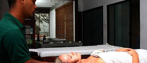 Sesión de masoterapia en una habitación con un espejo grande, armarios de madera y una ventana.