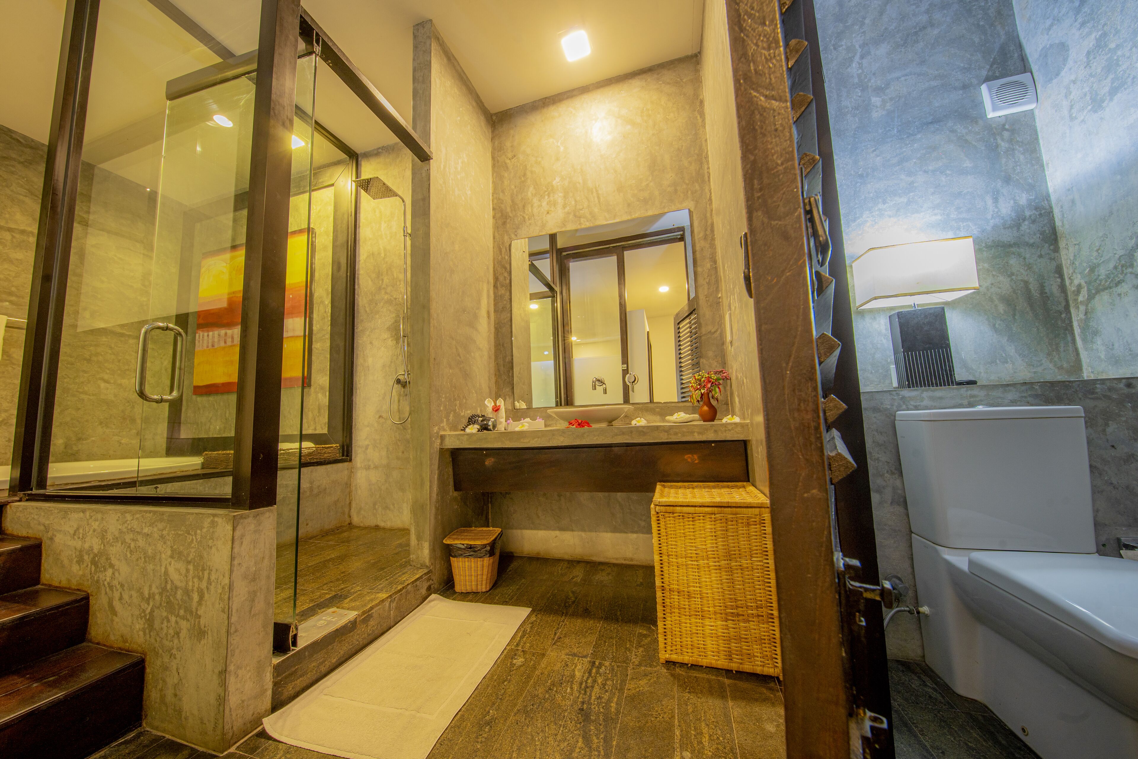 Un baño moderno con cabina de ducha de vidrio, un espejo grande y un inodoro blanco.