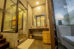Un baño moderno con cabina de ducha de vidrio, un espejo grande y un inodoro blanco.