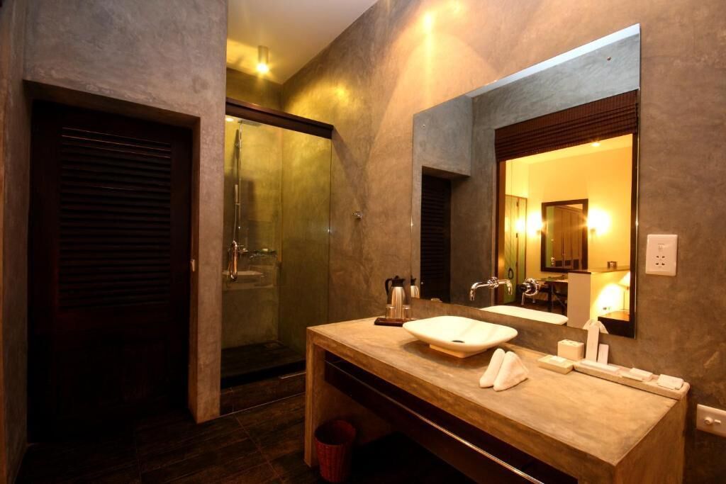 A modern bathroom with a large mirror, a sink, and a shower area.