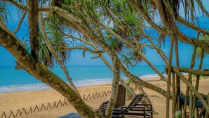 A beach with lounge chairs and a wooden fence. - Temple Tree Resort & Spa (Induruwa)