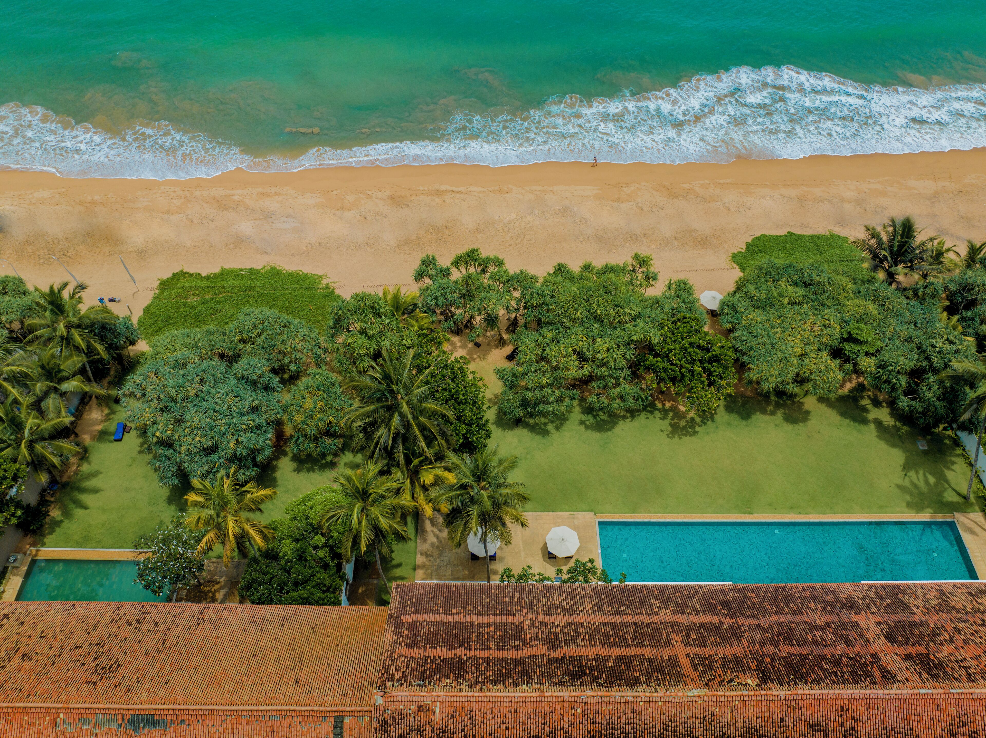 Vista aérea de una playa con piscina y exuberante vegetación.