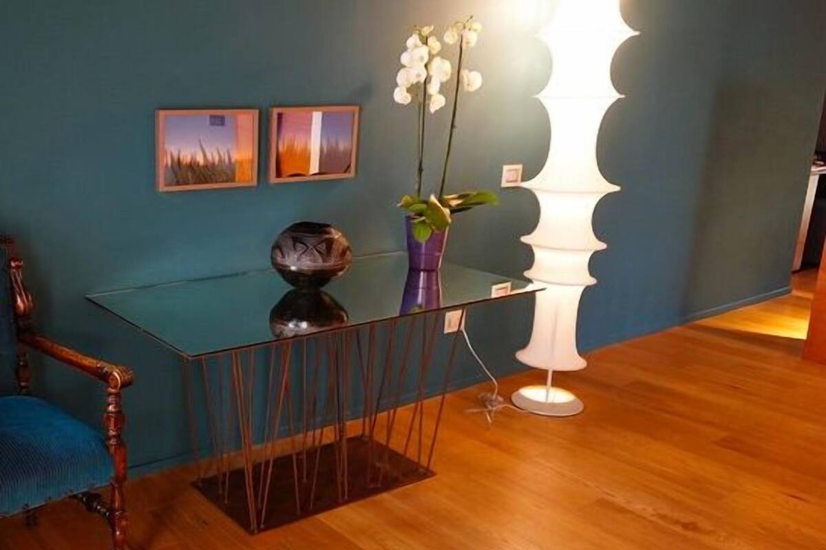 A reception desk with a glass top, a tall white floor lamp, and two framed pictures on the wall.
