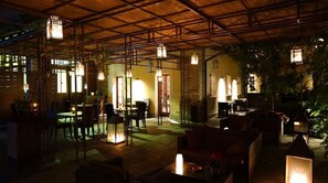 An outdoor dining area with tables and chairs, surrounded by greenery and illuminated by hanging lanterns. - Hotel Mulino Grande (Cusago)