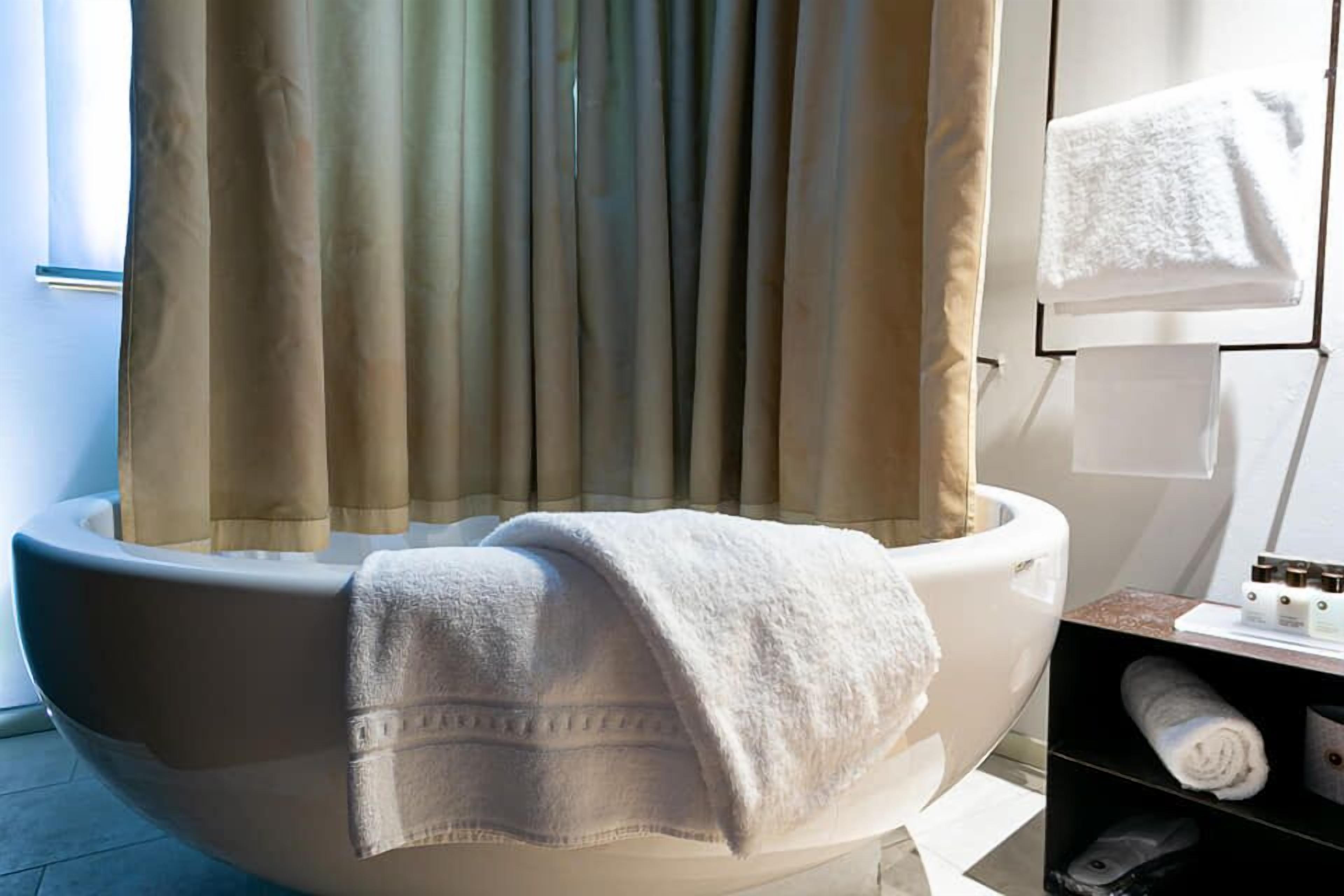 Ein modernes Badezimmer mit einer großen Badewanne, einem Handtuchhalter und einem Ablagefach mit Toilettenartikeln.