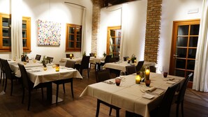 A restaurant with multiple tables set for dining, featuring white tablecloths, candles, and wine glasses. - Hotel Mulino Grande (Cusago)