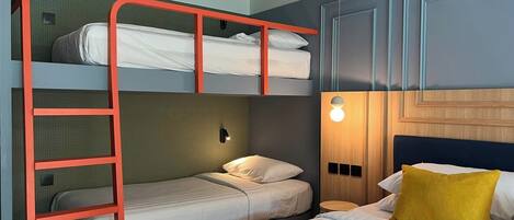 A room with bunk beds, a wooden headboard, a bedside lamp, and a bed with a striped bedspread.