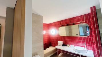 A modern bathroom with red tiled walls, a white sink, and a mirror above it.