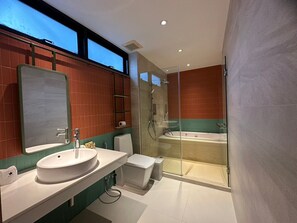 A modern bathroom with a large mirror, a sink, a toilet, and a glass-enclosed shower area with a bathtub. - Banlansuan Resort (Cha-am)