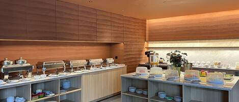 Eine moderne Küche mit Holzausstattung, einer zentralen Kochinsel mit Kaffeemaschine und einem Deckenventilator.