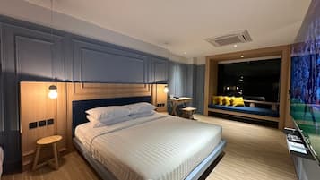 Habitación de hotel moderna con una cama grande, mesitas de noche, un escritorio y una ventana con vistas al cielo nocturno.