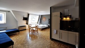 A compact room with a bed, a small dining table, and a kitchenette. - Five Elements Hostel (Frankfurt)