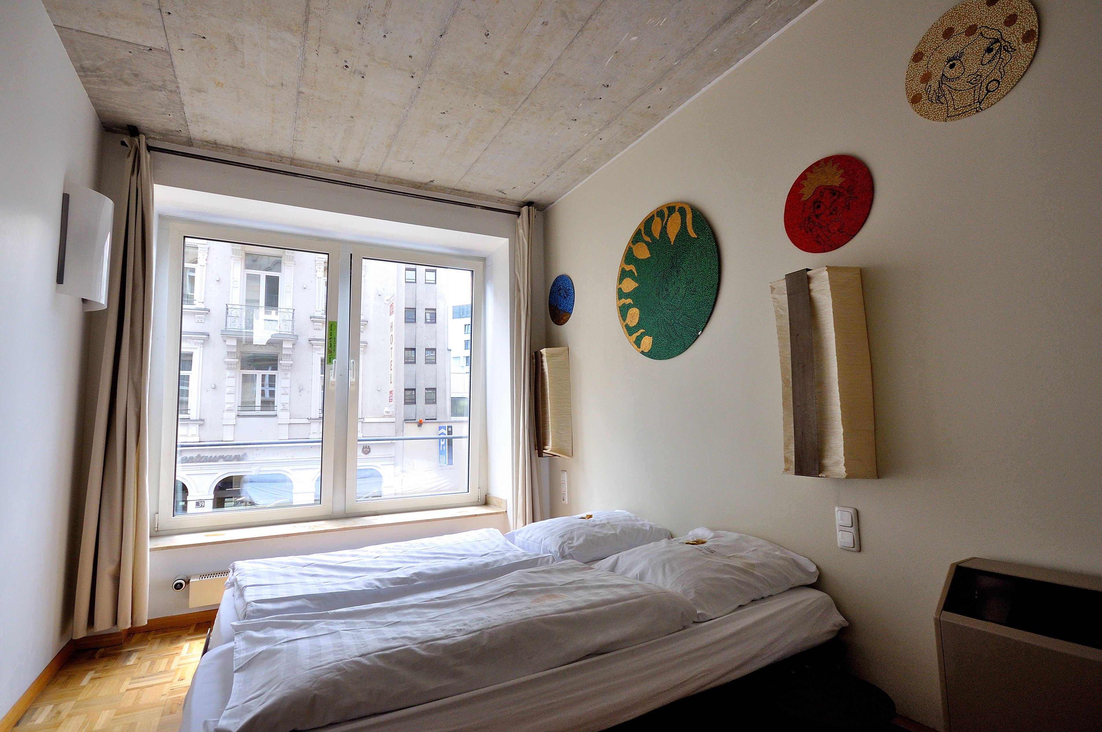 A hotel room with a large window, a bed, and wall decorations.