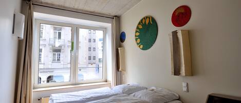 A hotel room with a large window, a bed, and wall decorations.