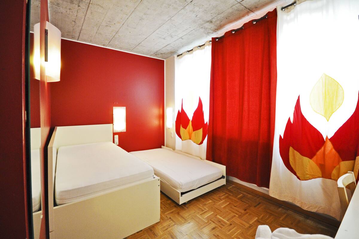 A room with a bed, a small table, and a chair.
