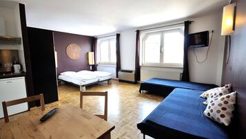 Una habitación compacta con cama, sofá, una mesita y televisión.