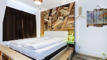 A bedroom with a wooden headboard, a bed with white linens, a wooden bench, and a wall-mounted map.