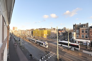A city street with tram lines, buildings, and a clear sky. - Will & Tate City Stay (The Hague)