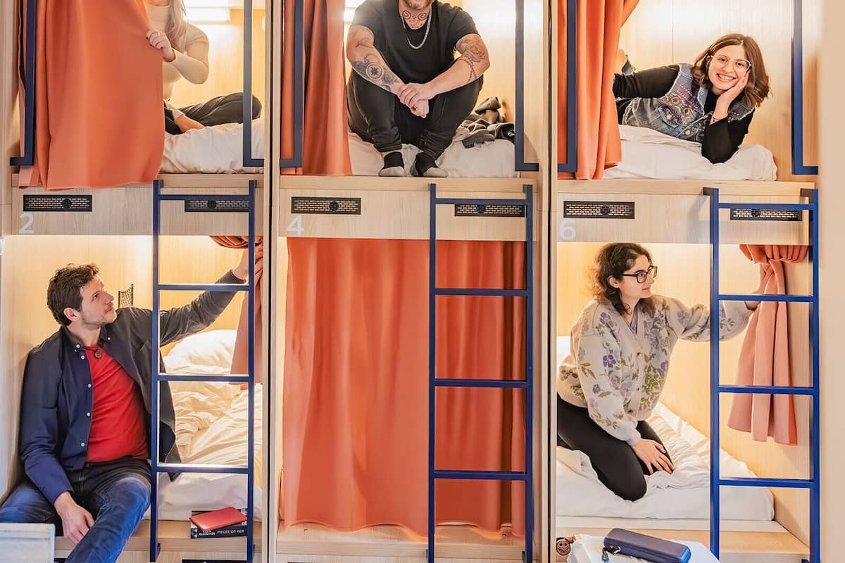 A hostel with bunk beds, each with a curtain and a number label.